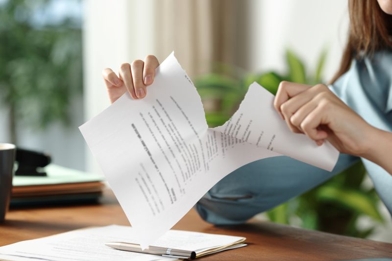 Person sitting at a desk tearing paper in half