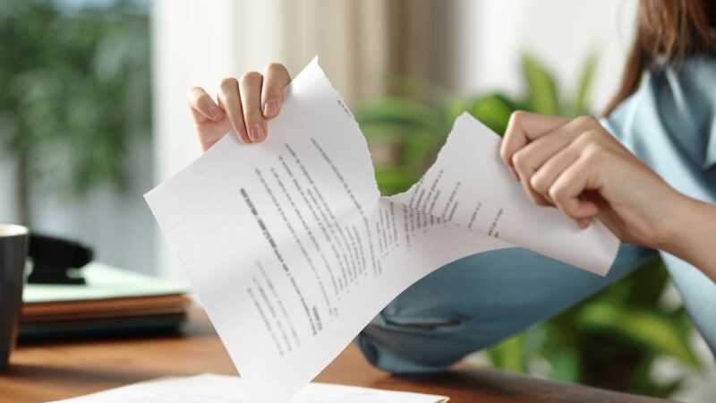 Person sitting at a desk tearing paper in half