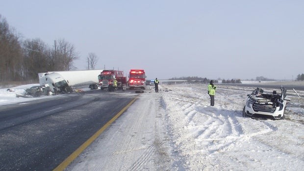 Major trucking crash on a snowy interstate involving two vehicles and a white semi-truck.  Firefighter trucks and first responders secure and investigate the scene.