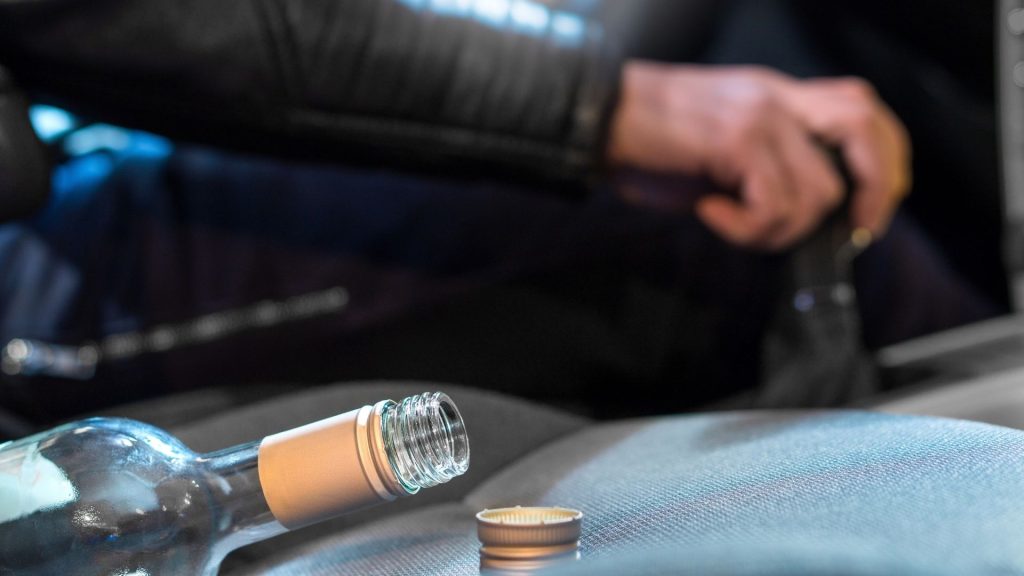 Person driving with liquor bottle in the passenger seat