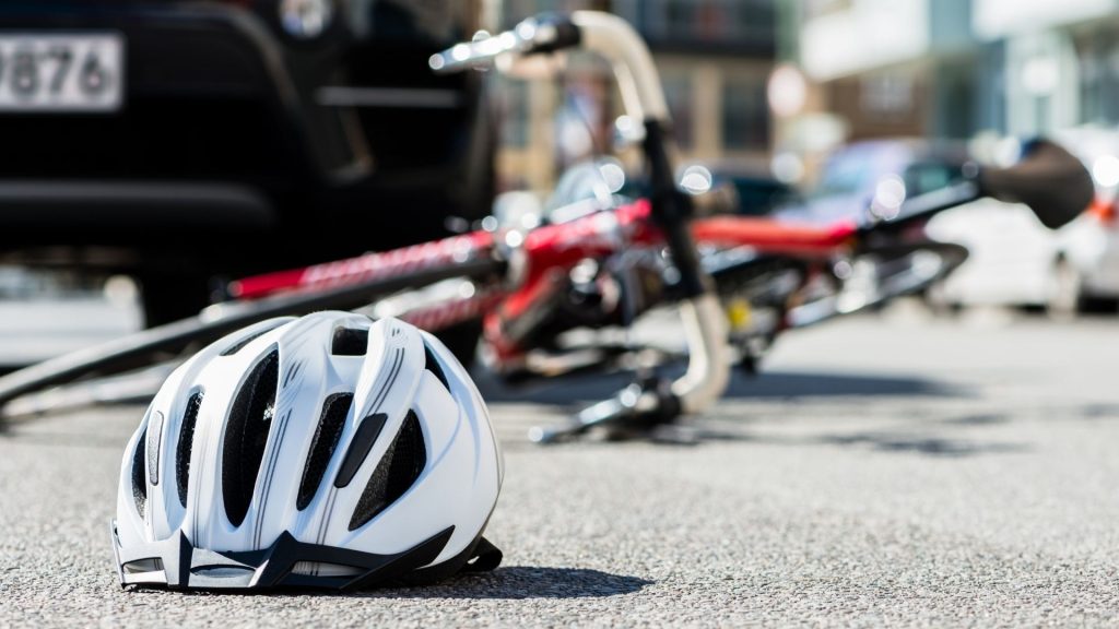 Bike on the ground next to a car post crash