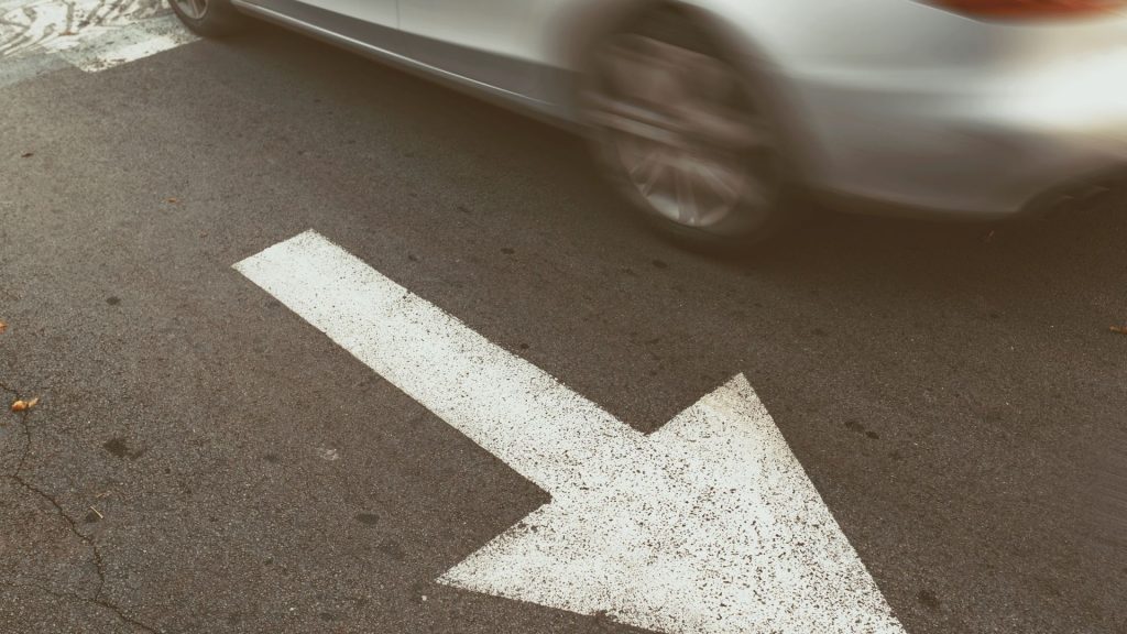 Car driving the wrong way beside an arrow pointing the direction they should be driving
